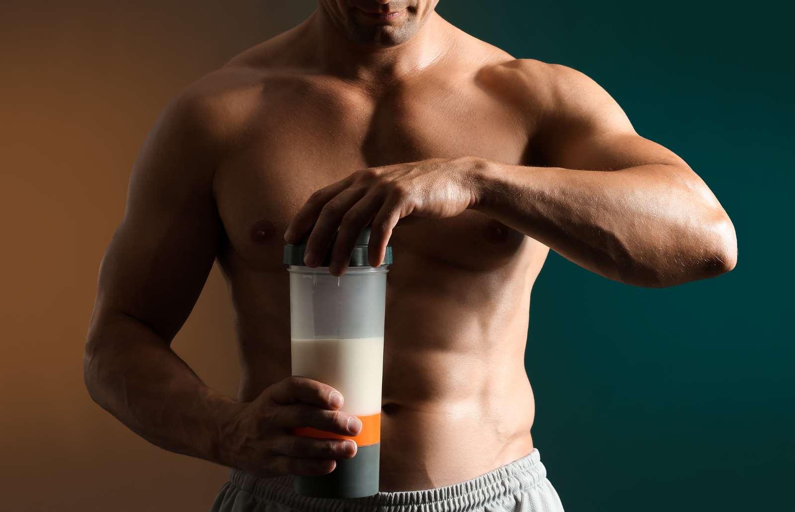 Male bodybuilder with protein shake on dark background