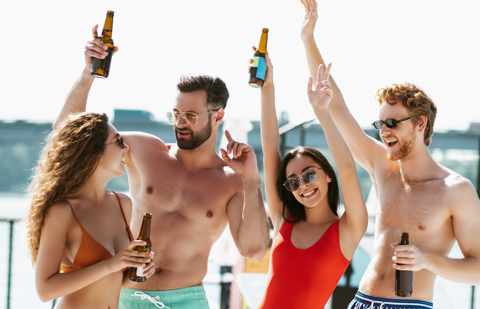 Happy people. Young people in swimming suits having good time drinking beer, feeling awesome and happy