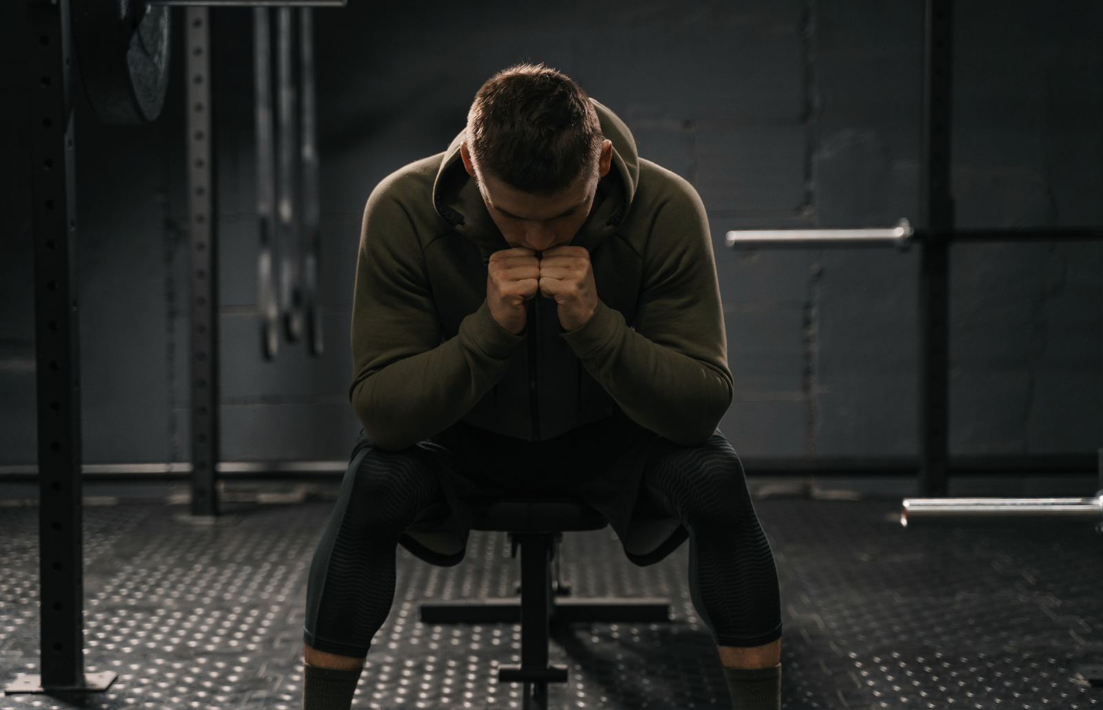 Sporty man sitting on gym bench suffering breakdown to overcome. Demotivation sport stress concept.
