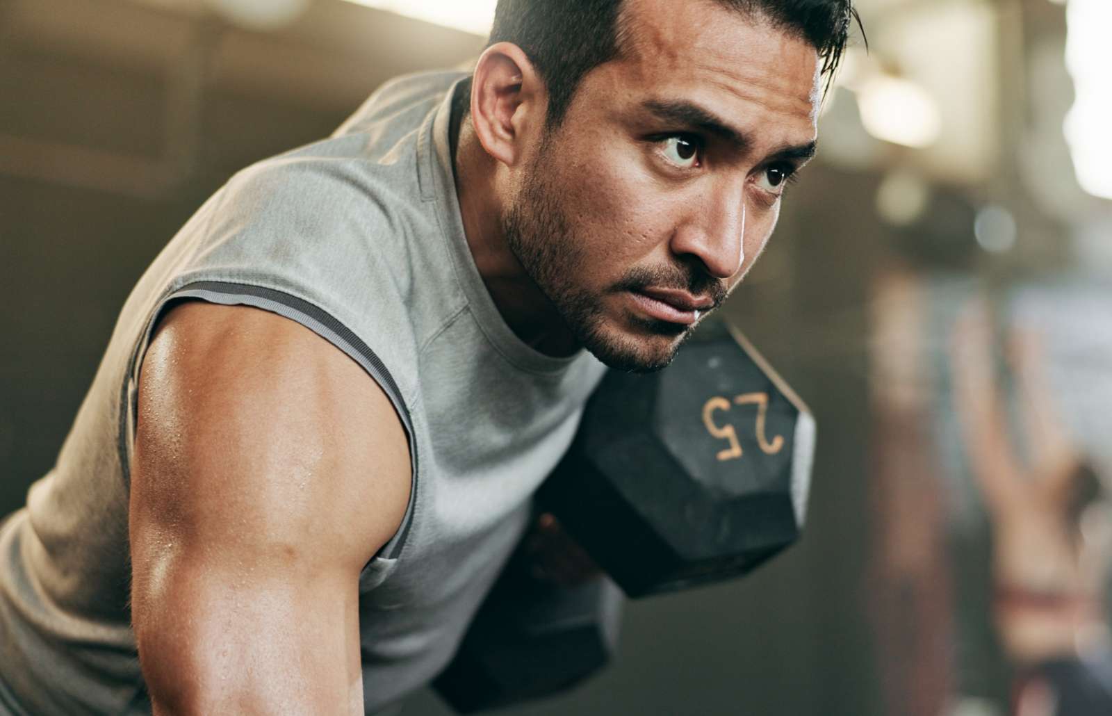 Serious man, dumbbell and weightlifting in workout, exercise or fitness at indoor gym. Active male person, bodybuilder or athlete lifting weight for intense arm training, strength or muscle at club