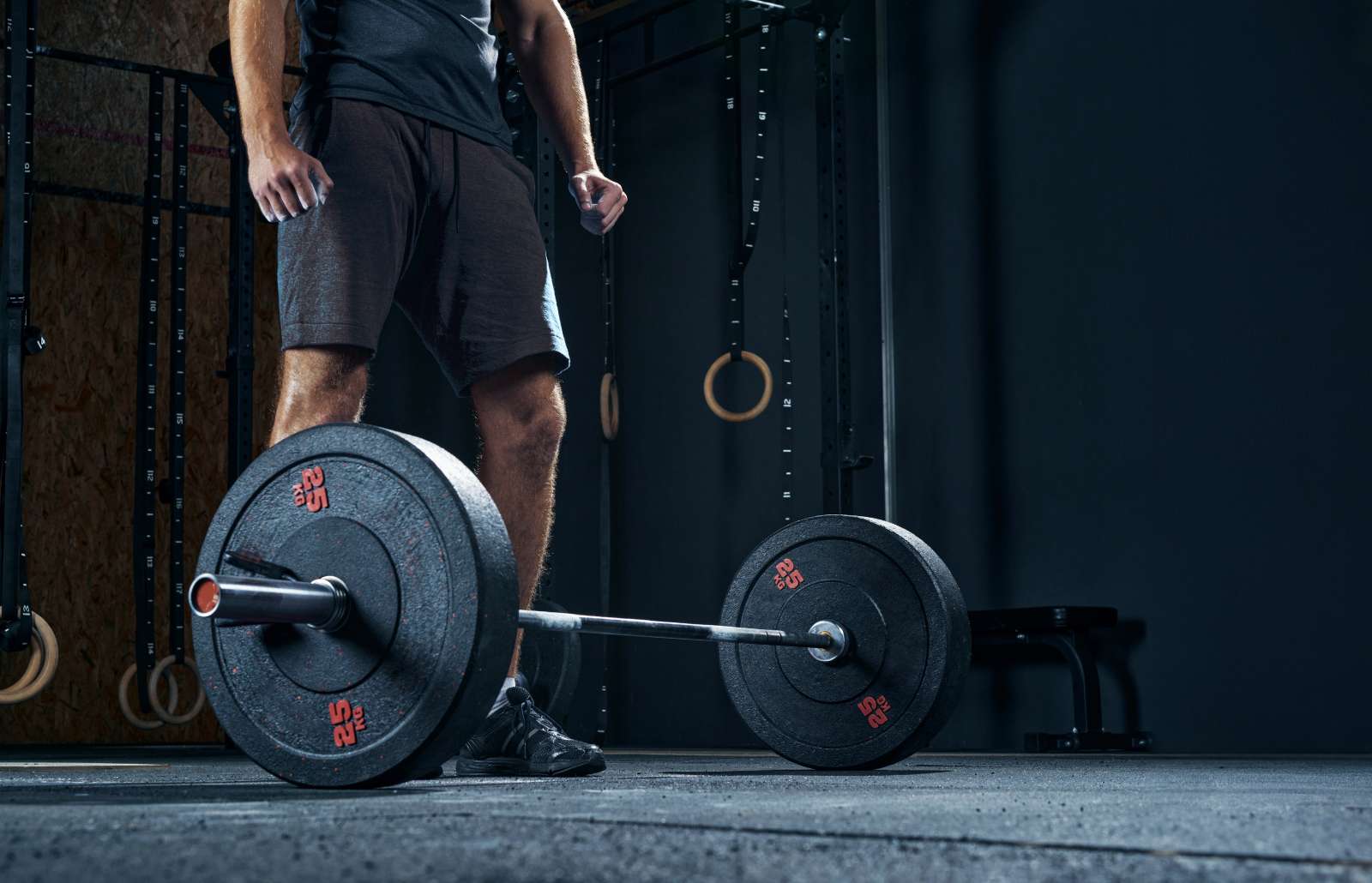Sportsman performing weight lifting exercise at gym, croped shot, low angle view focus on barbell.
