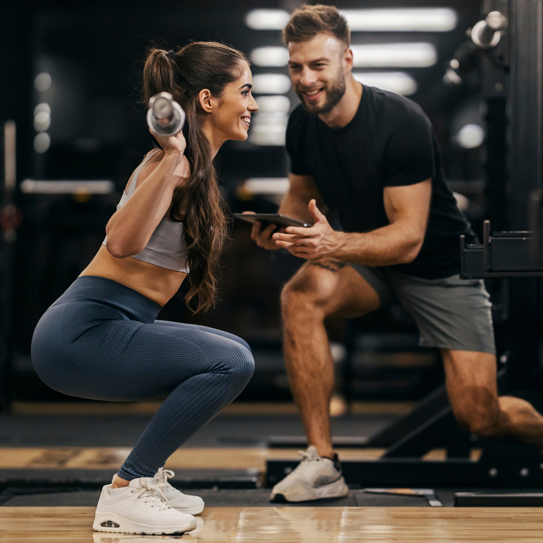 Personal trainer working closely with a female client during a strength training session at Strength Lab