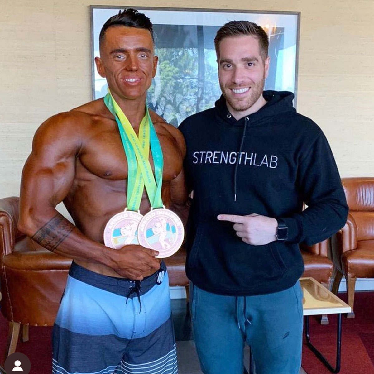 Client holding medals backstage after successful bodybuilding competition
