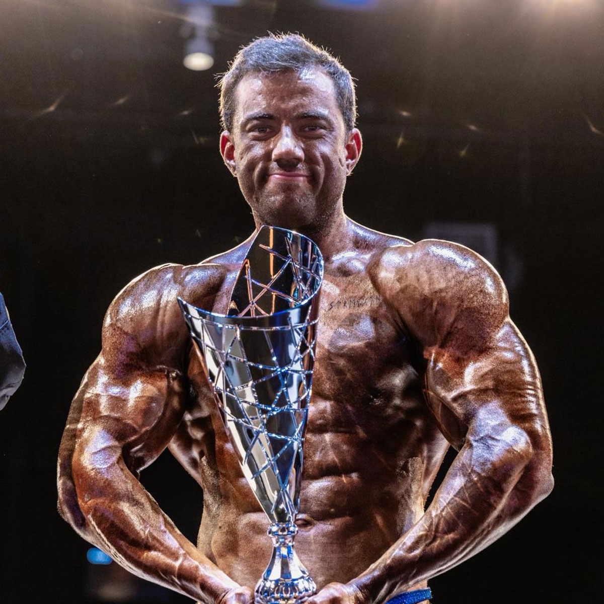 Male bodybuilding athlete flexing on stage after expert coaching with Strength Lab