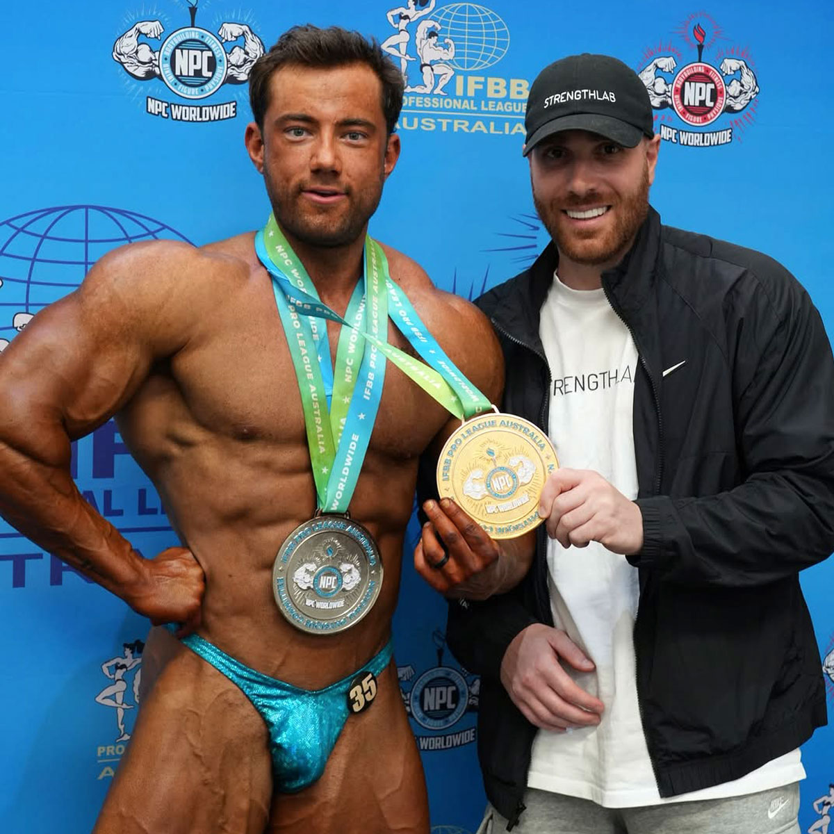 Client showing off medals after contest prep success with Strength Lab