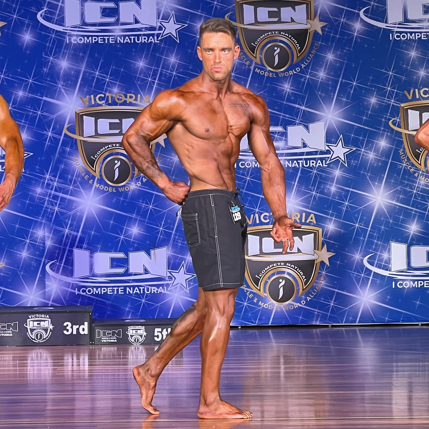 StrengthLab-Comp25 client posing on stage after months of bodybuilding prep with Strength Lab