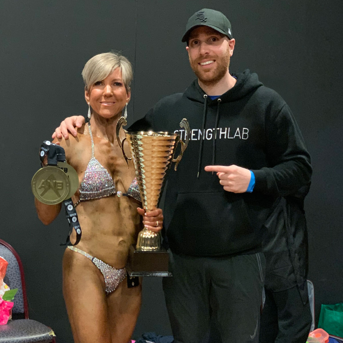 Client showing off trophies after contest prep success with Strength Lab