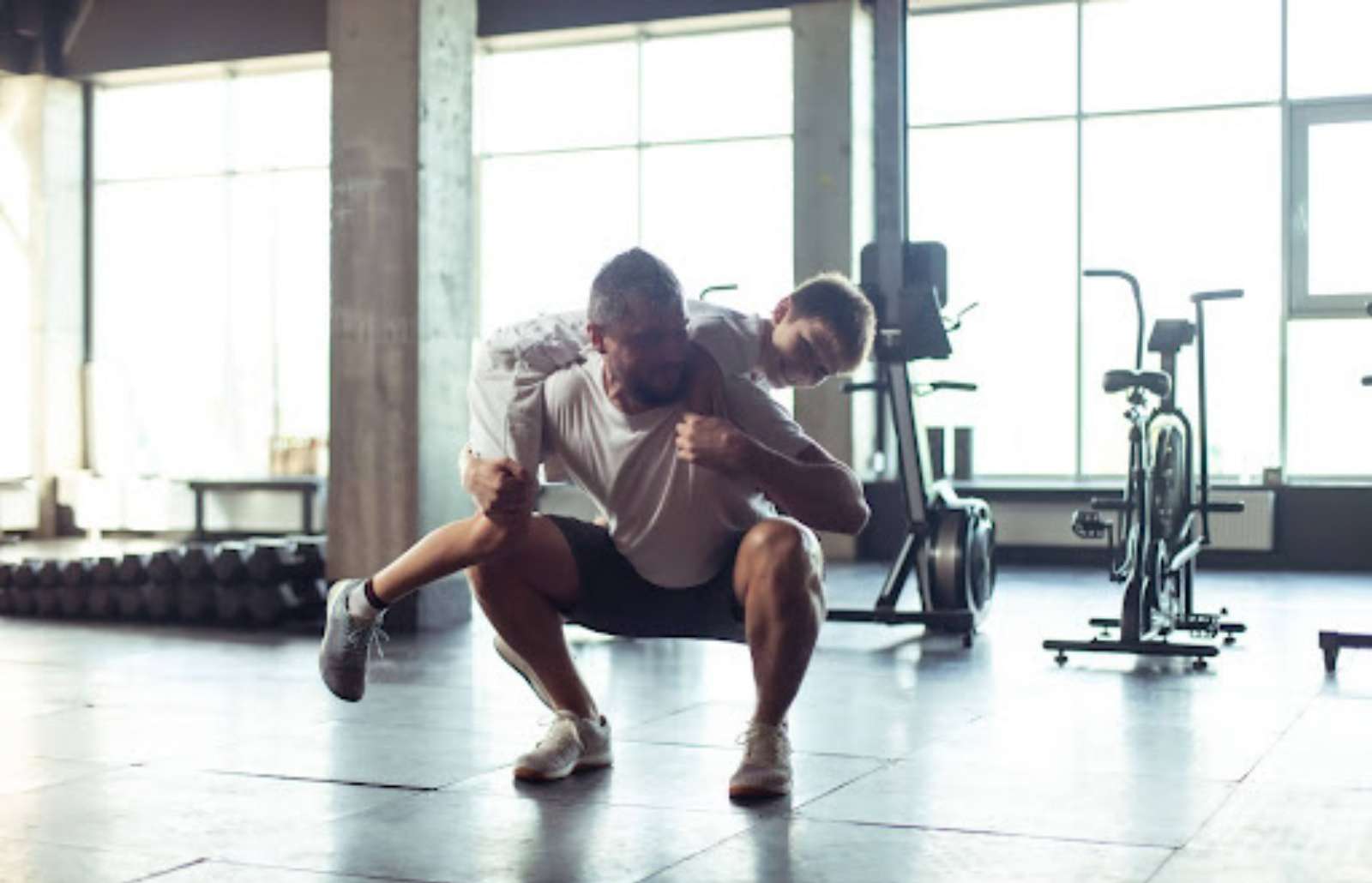 A father lifting his young son in a gym